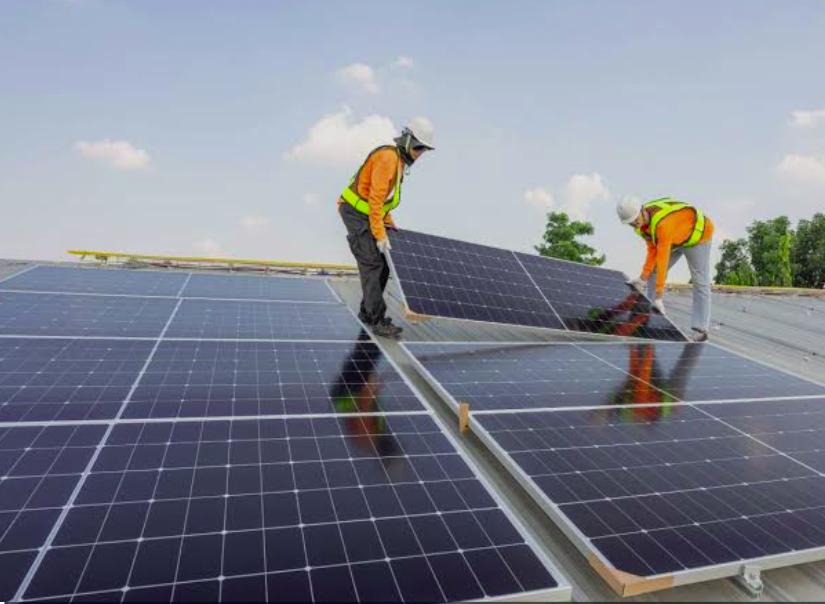 Neagle Electricals And Solar engineers carrying a solar panel on a rooftop in Kenya